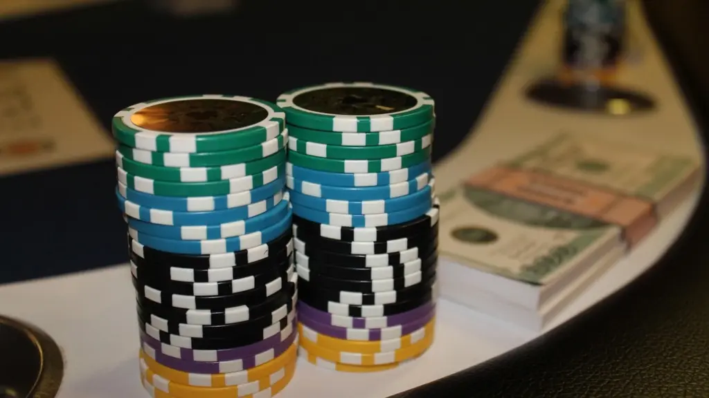 Twee stapels pokerchips en een stapel bankbiljetten op een pokertafel.