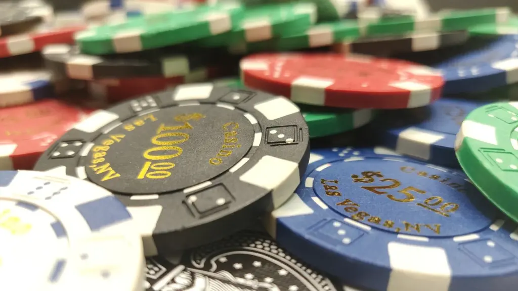 Een stapel kleurrijke pokerschips en een speelkaart op een tafel.