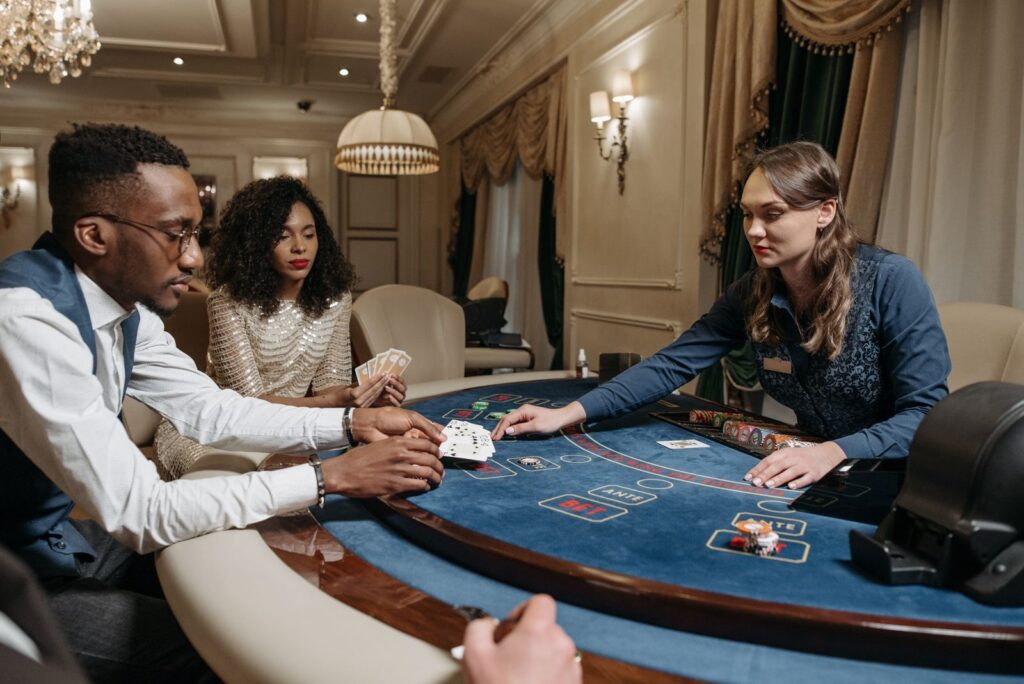 Spelers en een dealer aan een speeltafel met kaarten en fiches in een casino