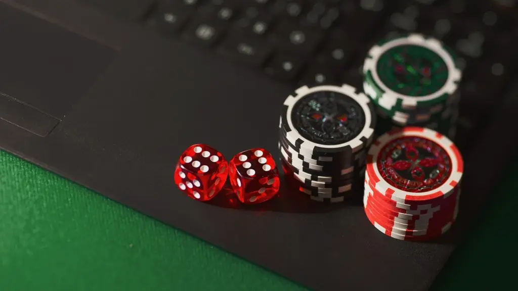 Pokerchips en rode dobbelstenen op een laptop op een groene tafel