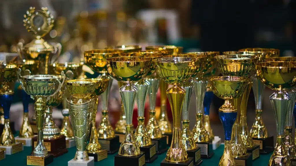 Gouden en zilveren bekers naast elkaar op een groene tafel
