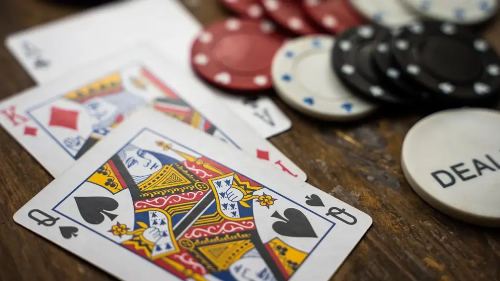 Speelkaarten en casinofiches op een houten tafel, inclusief een dealer-fiche.
